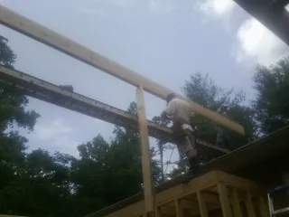 Carpenter setting a ridge beam over a new addition frame — Ice Dam Removal by Roofing Brothers in Convent