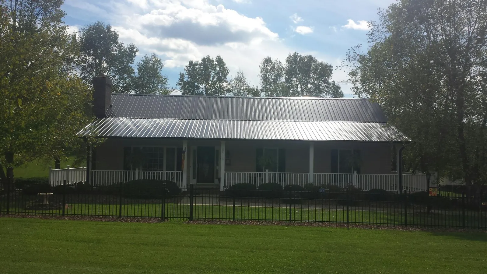 Gray metal roof on a brick ranch with a full width front porch — Gutter Guard Installation work by our crew in Convent