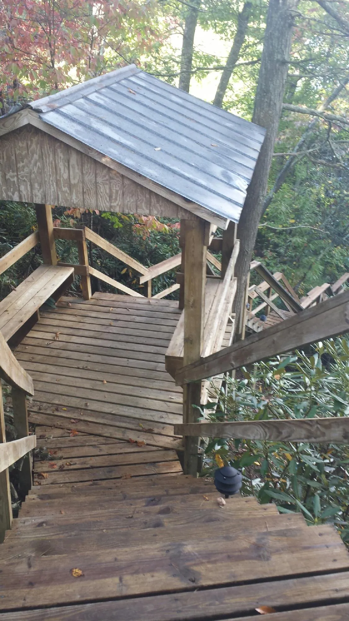 Metal roofed shelter over wooden steps on a wooded walkway — Skylight Repair & Installation work by our crew in Convent